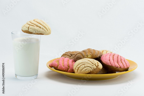 A cold glass of milk and colorful assortment of Mexican concha bread photo