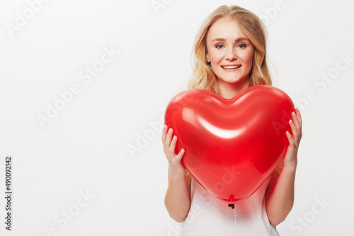 Would you be mine. Cropped view of a young woman holding a red heart in a studio. © Sanne B/peopleimages.com