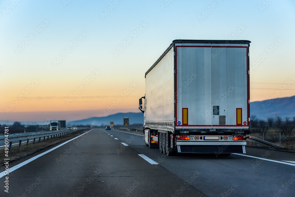 White Transportation Truck on a highway road under blue sunrise sky