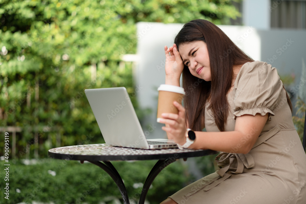 Asian woman is using her laptop to check email and work via the internet with a coffee next to her ,Working from home concept. Asian woman is using her laptop to check email and work via the internet with a coffee next to her ,Working from home concept.