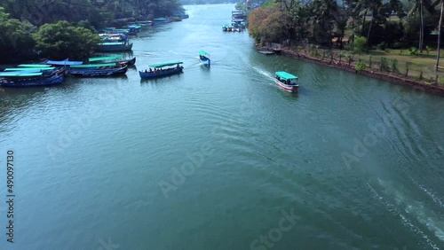 Small blue ferryboat floats on Nerul river in Aguada, Goa, india. A crowd of people on boat and on shore. Aerial view. photo