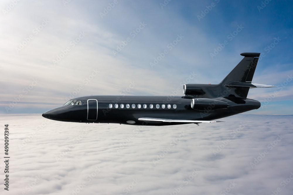 Black modern luxury executive business jet flies in the air above the clouds - obrazy, fototapety, plakaty 