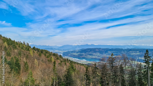 Scenic view on the Drava river in the Rosental valley on the way to Sinacher Gupf in Carinthia, Austria. Forest in early spring. The Hohe Tauern mountain range can be seen in the back. Sunny day. Hike