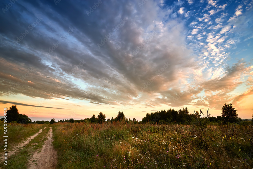Scenic countryside landscape with rural dirt road at sunrise. Summer landscape.