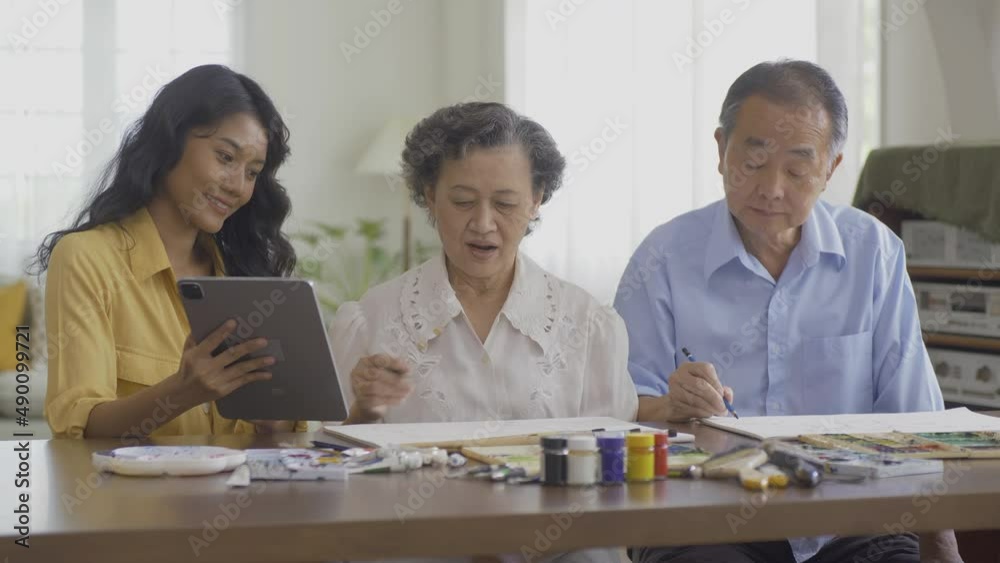 Female teacher teaching senior woman to paint picture at living room. Healthcare, Lifestyle and Hobby concept. Female teacher teaching senior woman to paint picture at living room. Healthcare, Lifestyle and Hobby concept.