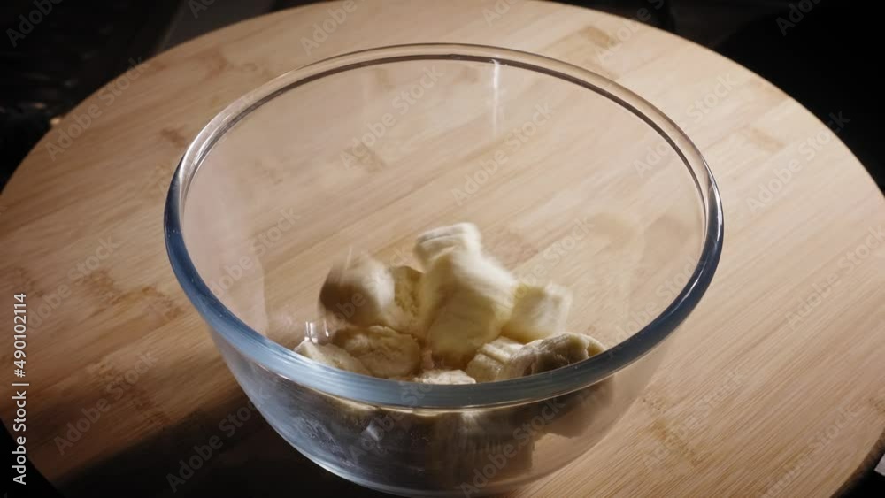 Chopped Ripe Bananas Dropping Into Glass Bowl On The Table. close up Chopped Ripe Bananas Dropping Into Glass Bowl On The Table. close up