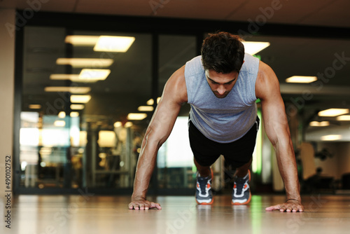 Pushing himself to new limits. A handsome man wearing sports clothing doing pushups in the gym.