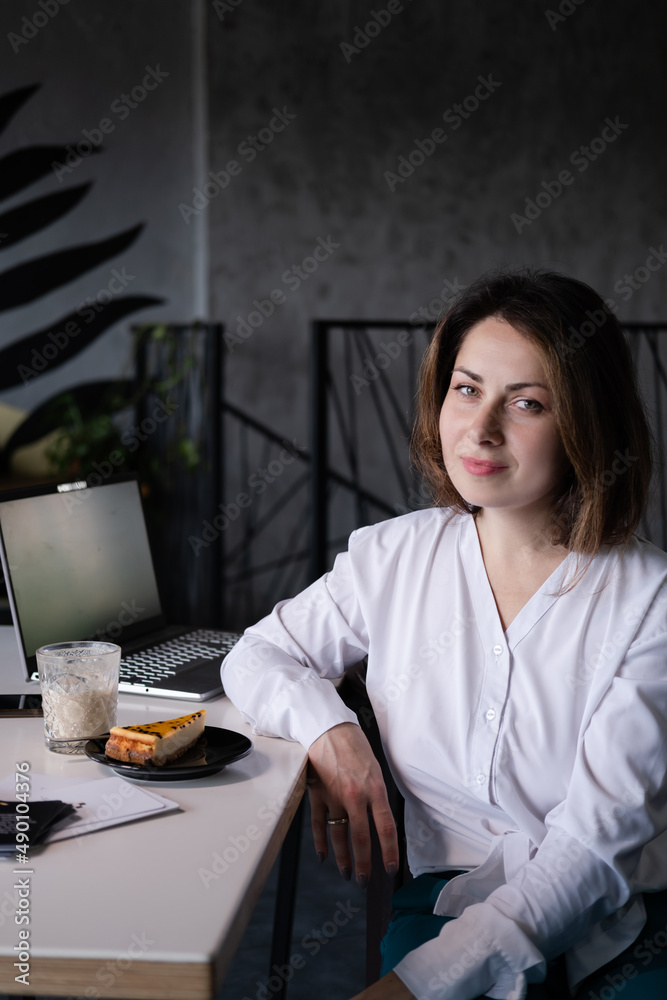portrait of confident brunette woman in white shirt in a cafe with a cup of coffee and dessert - piece of pie cake. portrait of confident brunette woman in white shirt in a cafe with a cup of coffee and dessert - piece of pie cake.