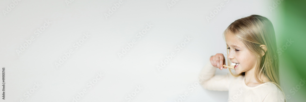 Cute little girl holding hands eco bamboo toothbrush on beige background. Sustainable living concept. Save the Planet for our children. Horizontal long banner for web design Cute little girl holding hands eco bamboo toothbrush on beige background. Sustainable living concept. Save the Planet for our children. Horizontal long banner for web design