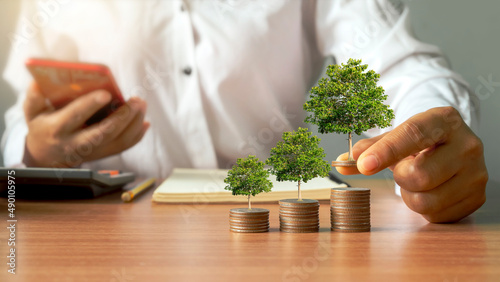 Businessmen holding coins and trees growing on piles of money. New business start-up ideas and economic-financial growth.