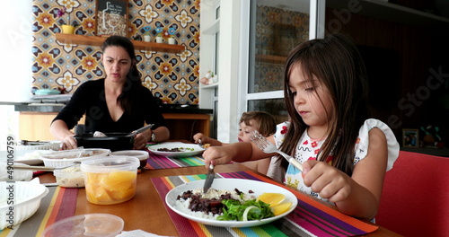 Casual family eating lunch at home together. Sisters with children gathered together  real life candid