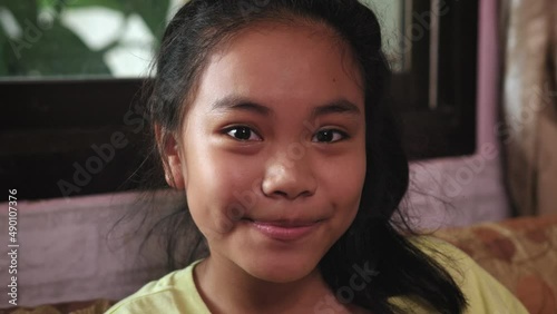 Young asian girl looking into the camera while sitting on sofa at home