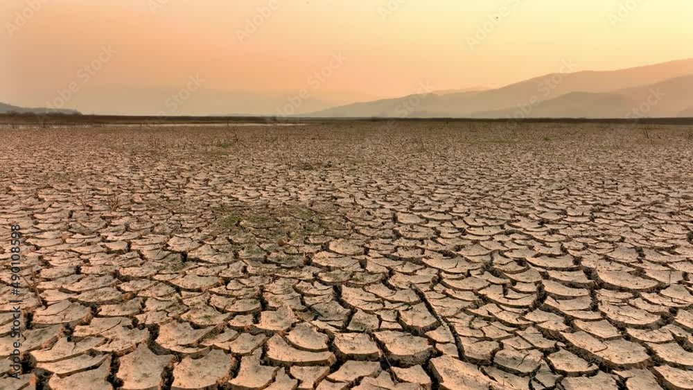 Drought and climate change, Landscape of cracked earth with orange sky after Lake drying on summer. Water crisis an impact of global warming.