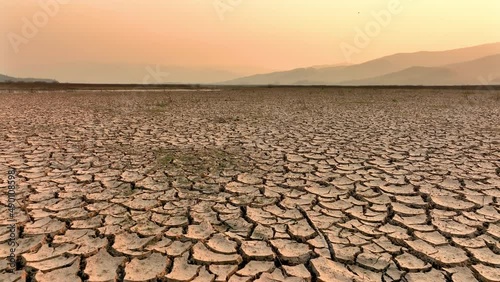 Drought and climate change, Landscape of cracked earth with orange sky after Lake drying on summer. Water crisis an impact of global warming. photo