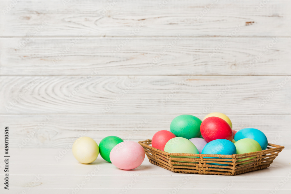 Multi colors Easter eggs in the woven basket on colored background . Pastel color Easter eggs. holiday concept with copy space