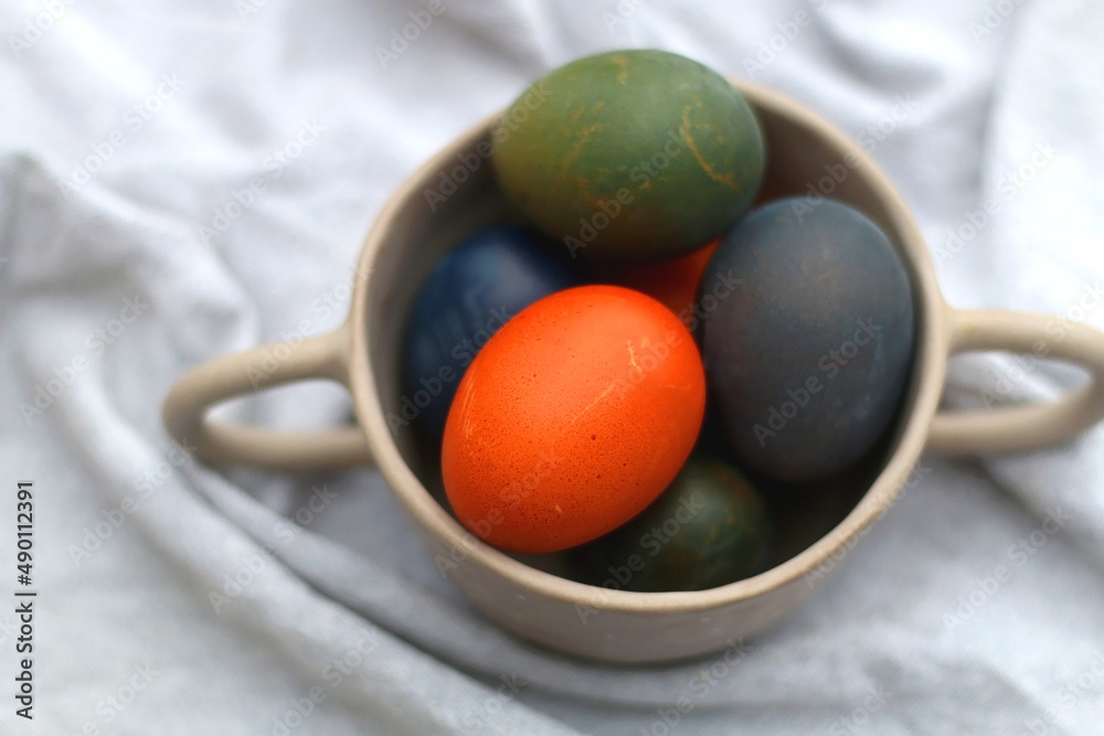 Ceramic bowl filled with painted Easter egss in jewel tones. Selective focus. Ceramic bowl filled with painted Easter egss in jewel tones. Selective focus.