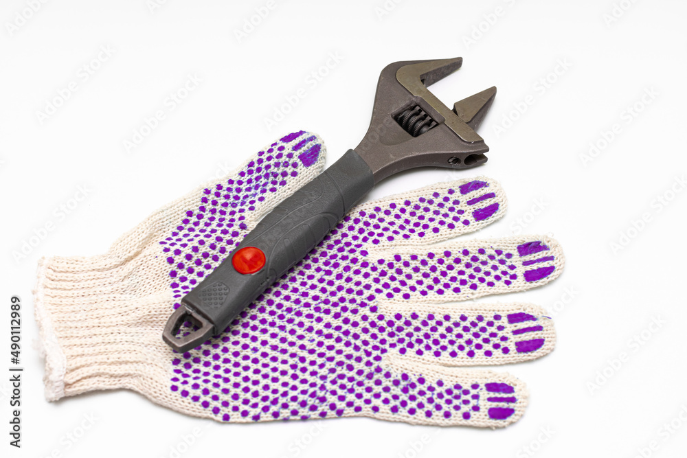 a metal adjustable wrench next to which lies a work glove a metal adjustable wrench next to which lies a work glove