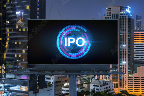 IPO icon hologram on road billboard over night panorama city view of Bangkok. The hub of initial public offering in Southeast Asia. The concept of exceeding business opportunities.