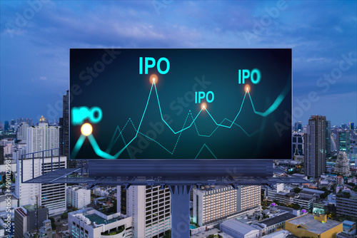 IPO icon hologram on road billboard over night panorama city view of Bangkok. The hub of initial public offering in Southeast Asia. The concept of exceeding business opportunities.