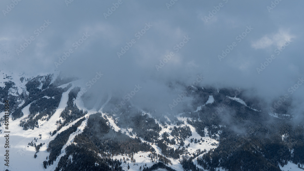 The image of the ski slopes covered by snow clouds.