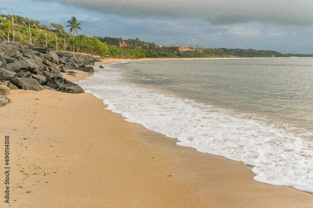 
Linda praia de areias escuras e poucas ondas, linda orla com paredão artificial de pedras e montanhas ao longe em porto seguro