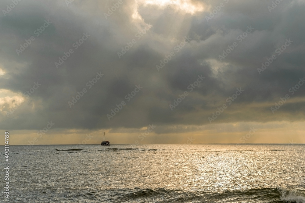 Lindo nascer do sol na orla de Porto Seguro, céu com nuvens, raios de sol no horizonte e barco ao longe