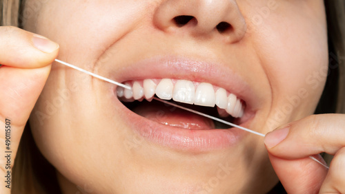 Cropped shot of a young caucasian woman flossing her teeth. Close-up. Oral hygiene, dental health care, morning and evening routine. Dentistry concept