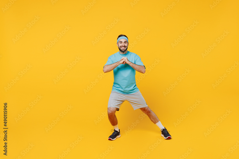 Fototapeta premium Full body fun young fitness trainer instructor sporty man sportsman in headband blue t-shirt spend weekend in home gym do lunges isolated on plain yellow background. Workout sport motivation concept.