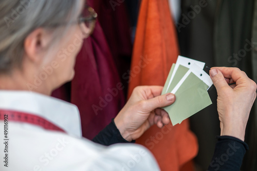 Clothes tags in hands of woman standing near rack