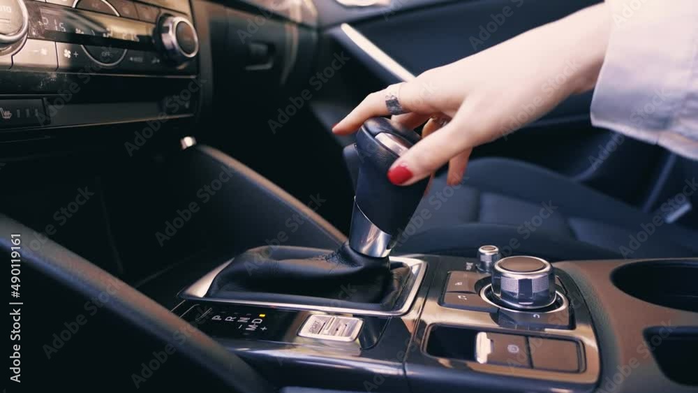 Hand of businesswoman use gear stick, change, shifting the automatic transmission in luxury gray car close up inside view at evening sunny. Hand of businesswoman use gear stick, change, shifting the automatic transmission in luxury gray car close up inside view at evening sunny.