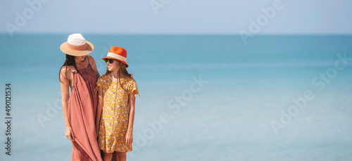 Beautiful mother and daughter at the beach enjoying summer vacation