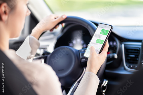 Using phone while driving car. Distracted driver texting while in vehicle. Irresponsible woman checking sms message with mobile cellphone in traffic. Holding smartphone in hand. Auto accident concept.
