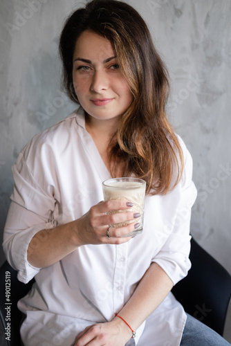 beautiful brunette woman with glass of coffee. confident lady in a cafe with a drink