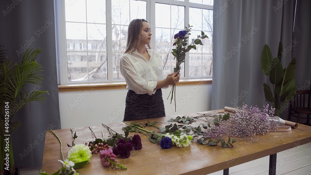 A young beautiful woman engaged in floristry begins to collect the best flowers for her flower arrangement. Floristry A young beautiful woman engaged in floristry begins to collect the best flowers for her flower arrangement. Floristry