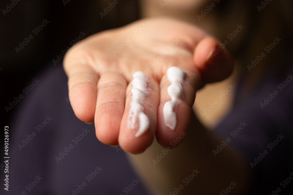 A person applying the correct amount of sunscreen for face and neck.