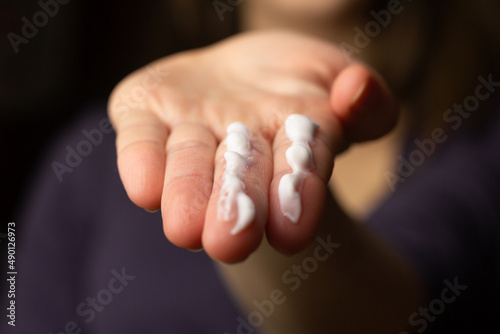 A person applying the correct amount of sunscreen for face and neck.