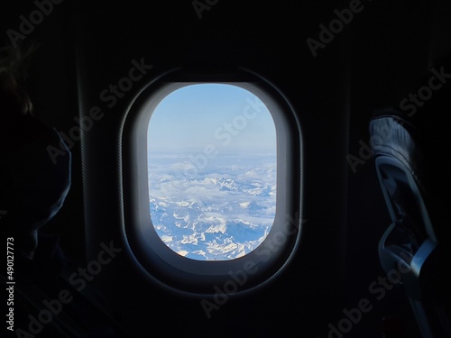 Panorama of the snow capped Alps in the window of an airplane flying over them