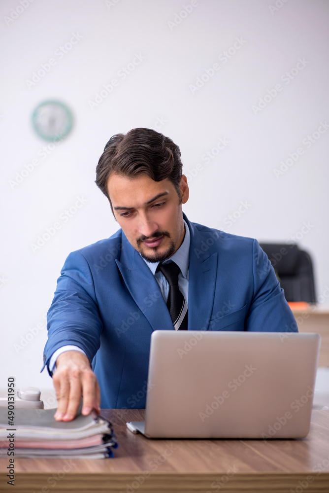 Young male employee unhappy with excessive work in the office Young male employee unhappy with excessive work in the office