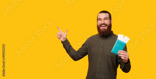 Banner size photo of a man holding a passport and pointing on the background. photo