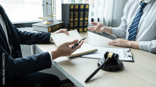 Male lawyer working on documents contract papers of the important case with the business customer and wooden gavel, brass scale in office