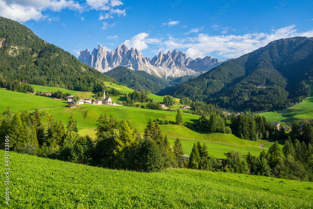 Green grassy meadows in the village of Santa Maddalena against the great peaks of the Odle Group, Val di Funes, Dolomites.