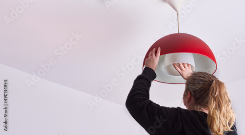 unrecognizable blonde woman changing a light bulb at home, DIY