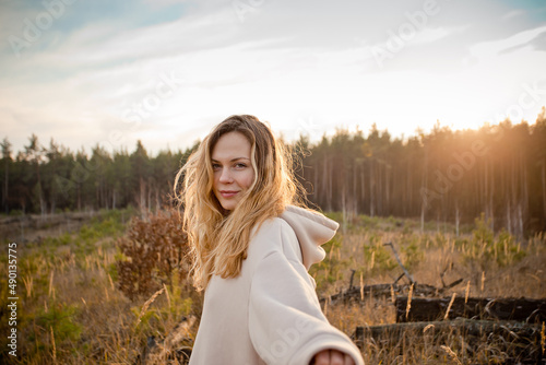Foto Young happy beautiful woman with curly blonde hair posing outdoors in the sunlig