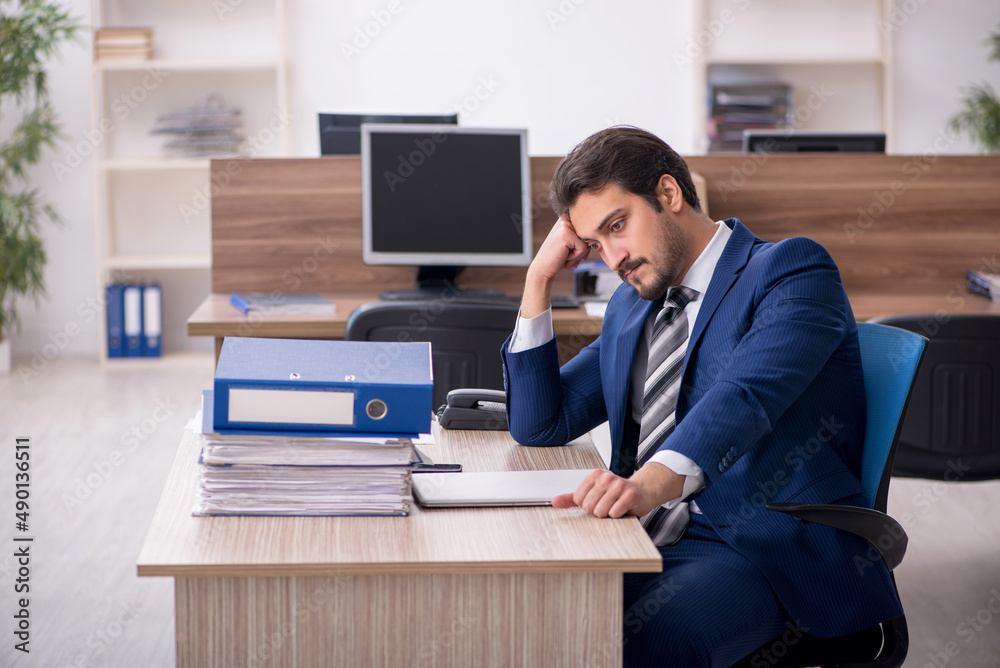 Young male employee and too much work in the office Young male employee and too much work in the office