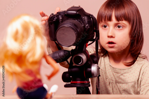 Child girl photographer is shooting portraits of doll © zwiebackesser
