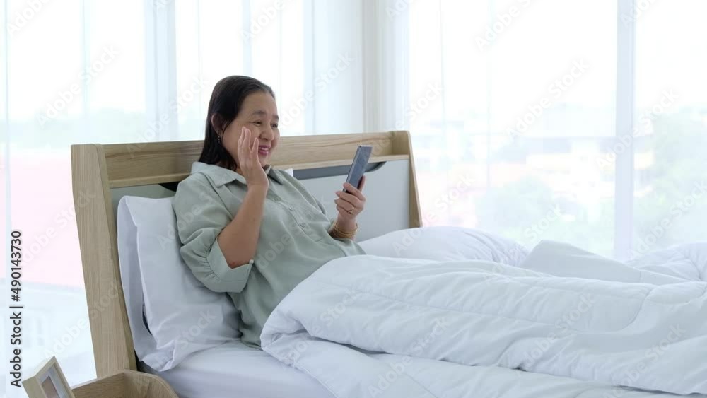 Happy senior woman enjoying using mobile apps texting typing messages sit on bed. Happy senior woman enjoying using mobile apps texting typing messages sit on bed.