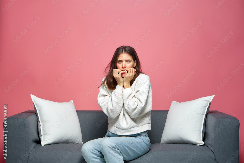 Nervous scared anxious woman biting nails, feeling fear, thinking about problem, sitting on sofa. Domestic violence Nervous scared anxious woman biting nails, feeling fear, thinking about problem, sitting on sofa. Domestic violence