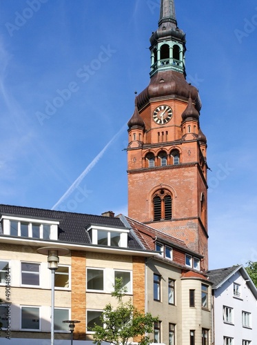 View of european building exterior and St. Laurentii church clock tower at intersection of Kirchenstrasse and feldschmiede in Itzehoe, Germany with clear blue sky background. photo