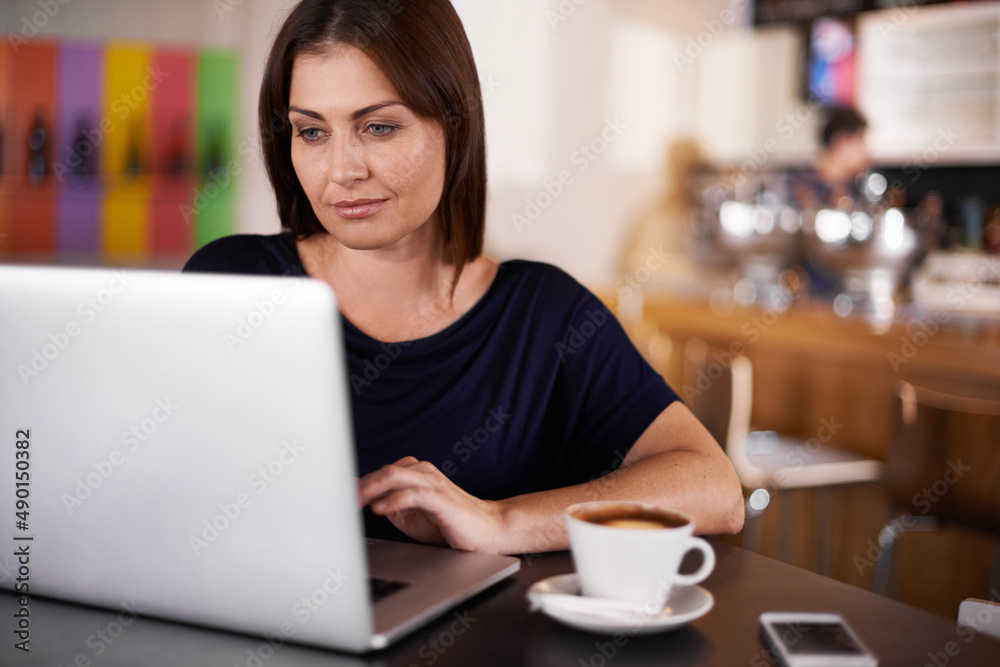 Getting some work done on the go. An attractive woman working on a laptop at a coffee shop. Getting some work done on the go. An attractive woman working on a laptop at a coffee shop.