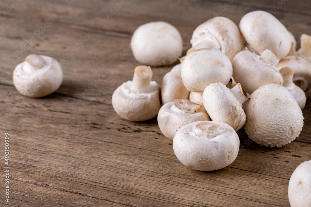 Fresh raw organic champignons heap on a wooden table.